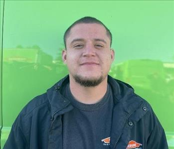 male employee standing in front of a green wall