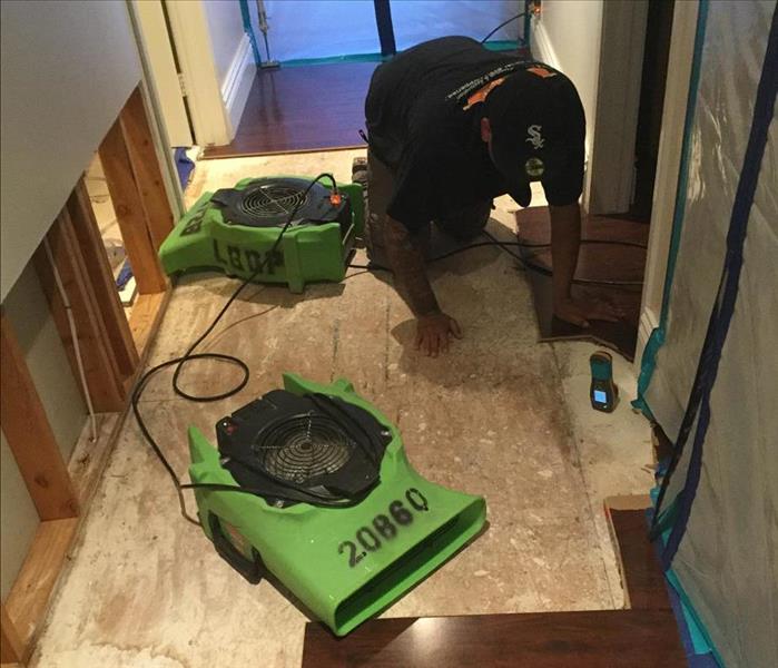 water restoration technician removing water damaged flooring