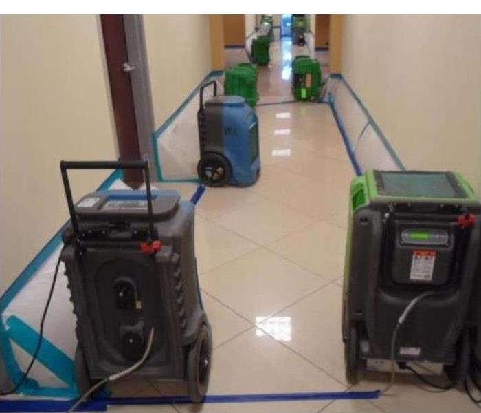 Dehumidifiers placed in a commercial hallway, water damage in hallway