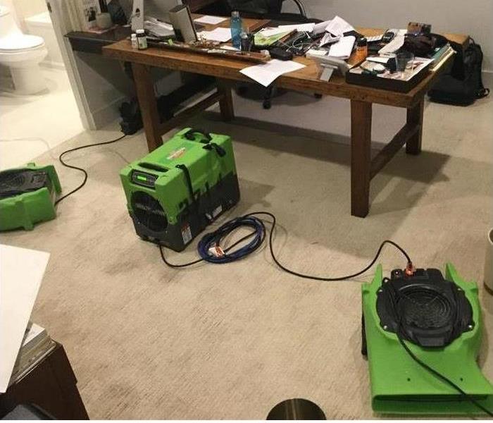 Restoration machines are cleaning water damage in an office