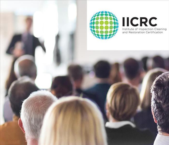 Group of people receiving training, IICRC logo.